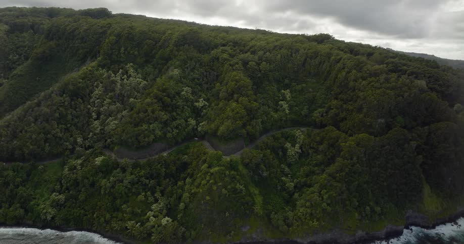 A winding road running high along the coast of a land mass covered in dense forest