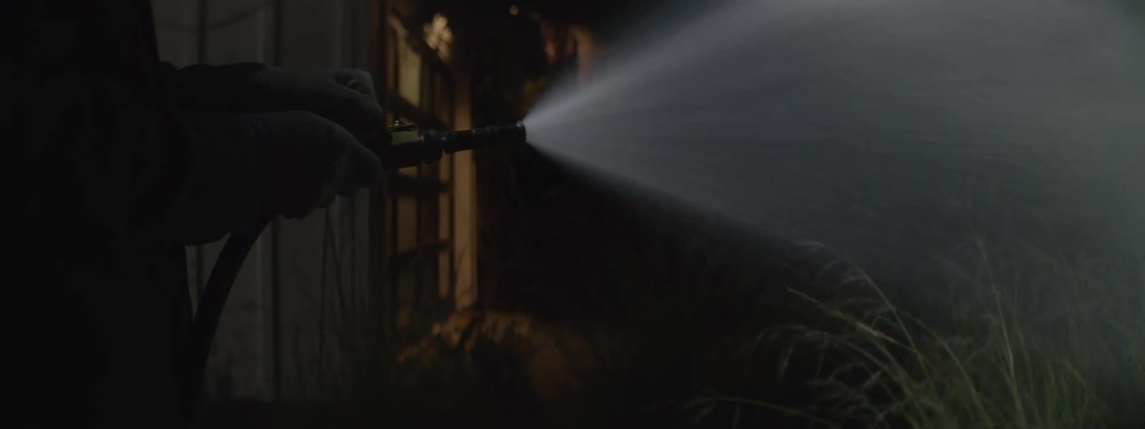 A man waters a plant in his front yard