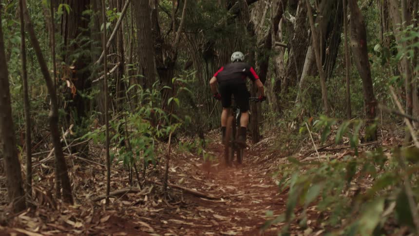 A man is riding a dirt bike through a forest