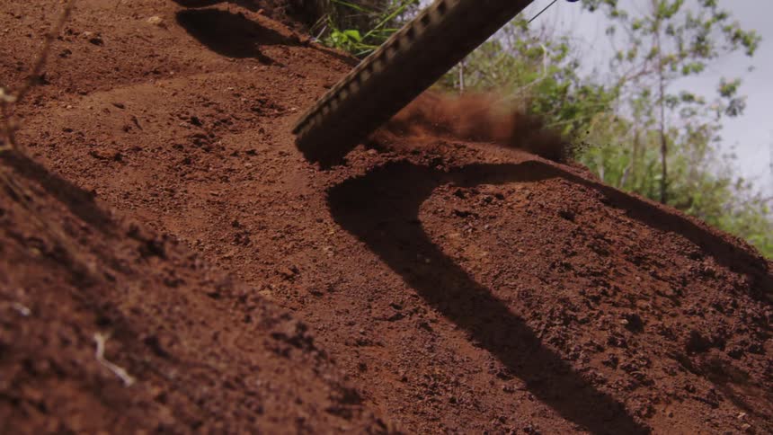 A close up of bike wheels are shown jumping over a dirt path