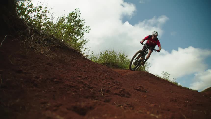 A cyclist rides a bicycle down a slope covered in dirt during the day