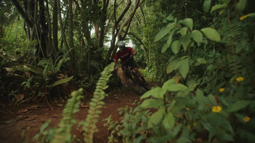 A man rides his back very fast down a dirt path in the woods