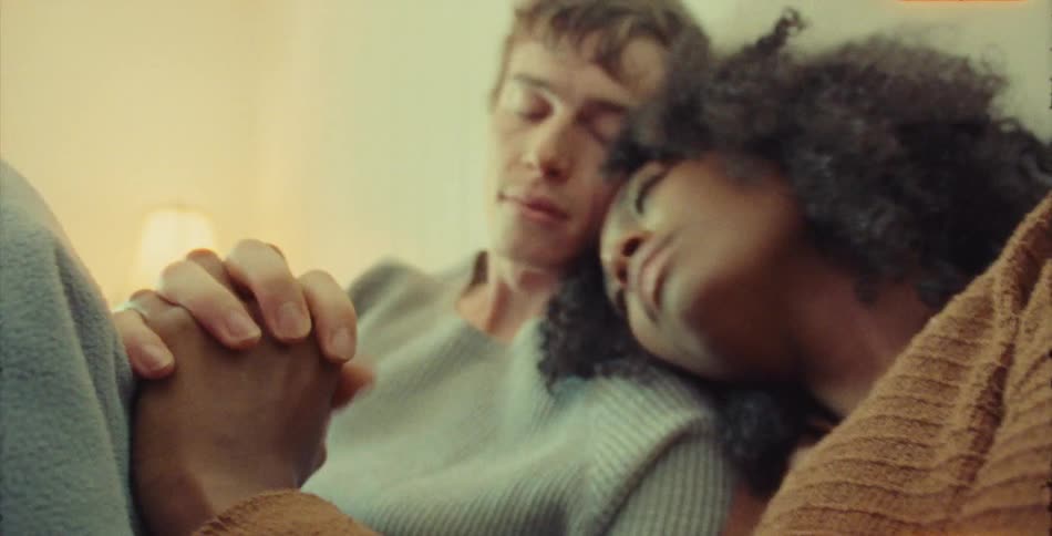 Couple cuddles against each other while holding hands