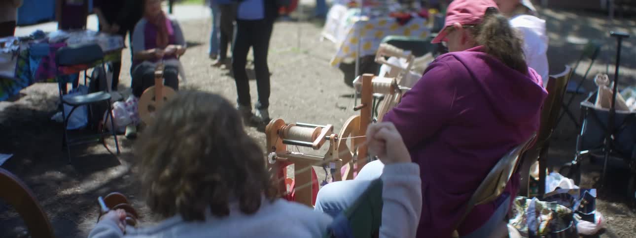 A group of women sit outside and spin wool