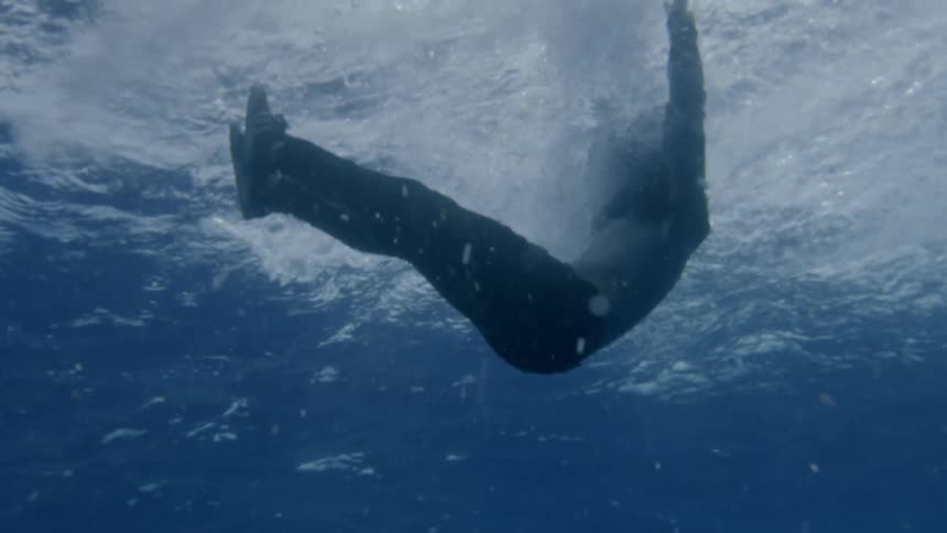 Alone man wearing clothes falling into the blue sea water