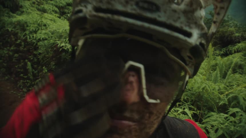Male cyclist standing on trail in dirty clothes touches his dirty face