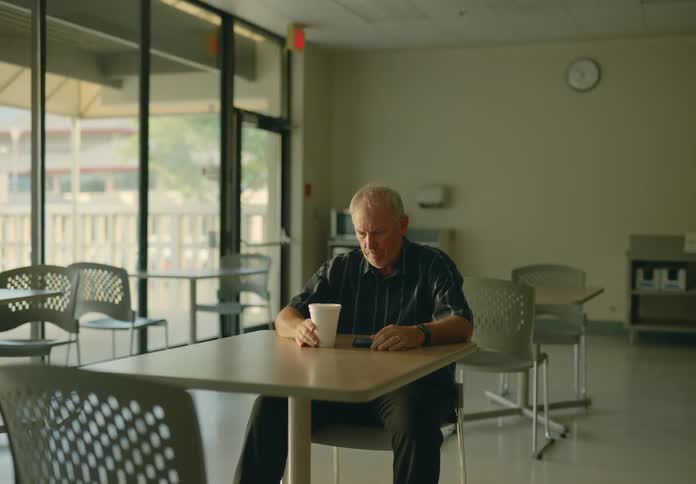 A man is sitting at a table with a cup of coffee