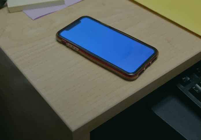 Person picks up smartphone from desk
