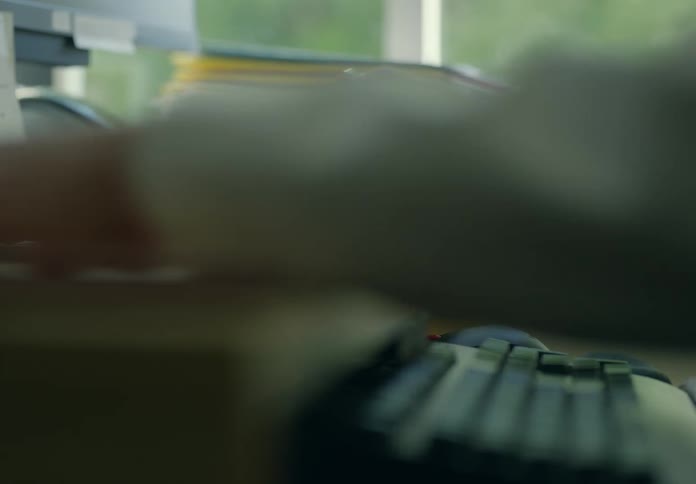 A person is sitting in their office and writing on paper