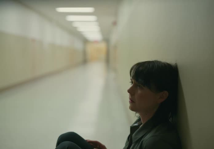 Introspective woman sliding down against the wall and sitting on the floor