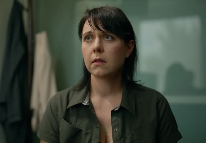 A woman is standing in a room looking around with a worried look on her face