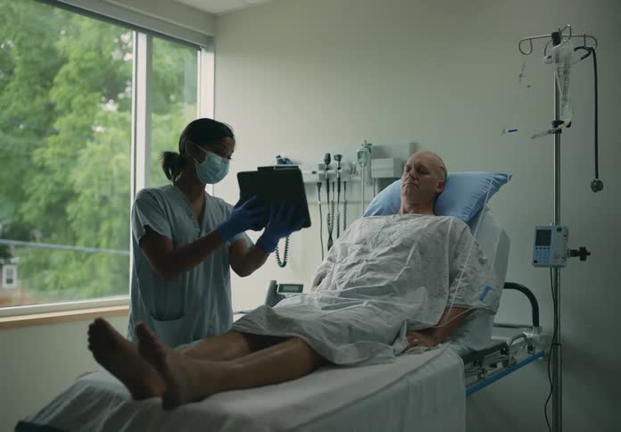 A nurse holding up a chart for a hospitalized patient