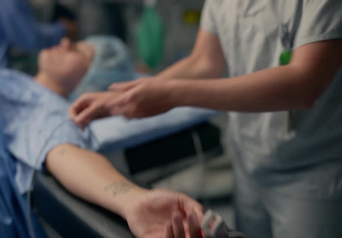 Nurse applies sensors to patient lying on operating table in surgery