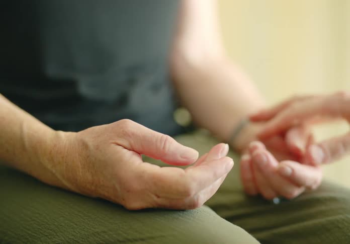 Physical therapist massages patients trembling hands and guides her in flexing them