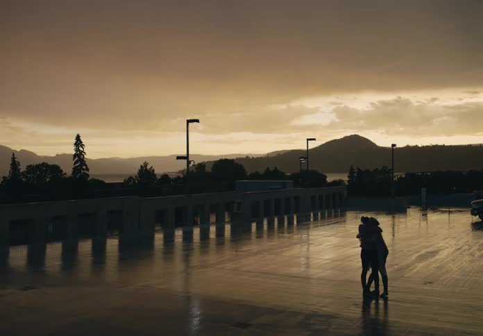 Two women run towards one another in a parking lot and hug