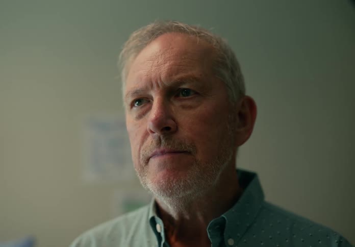 A man is standing up in a room during midday