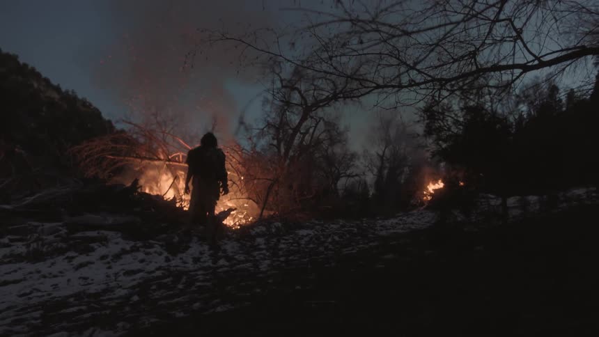 Man standing in front of bonfire at night