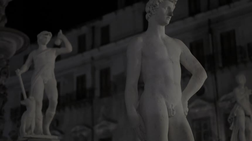 Statues on a stair railing stand out against a dark sky and a building
