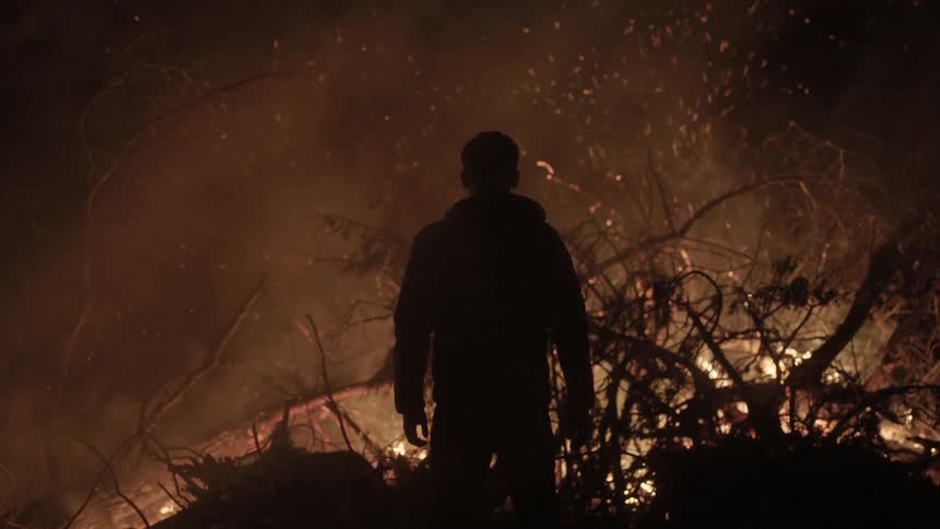A man stands in front of a large fire