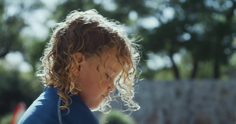 Side profile of blonde girl with curly hair looking down