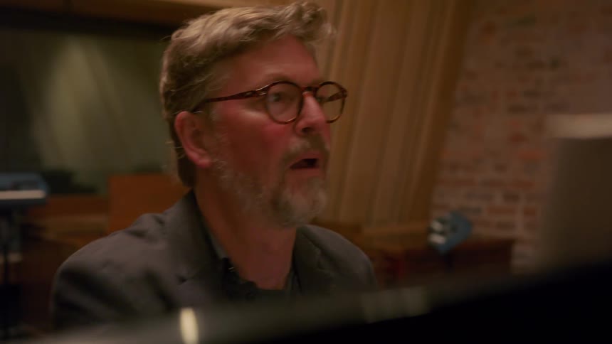 A man is sitting at a piano with his music book propped up in front of him and he turns the pages