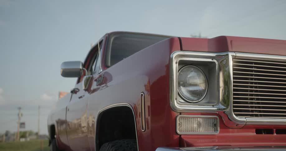 A man walks past a red pickup truck in a parking lot