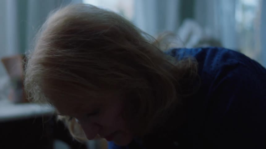 A woman at home sits and cries as she looks through items