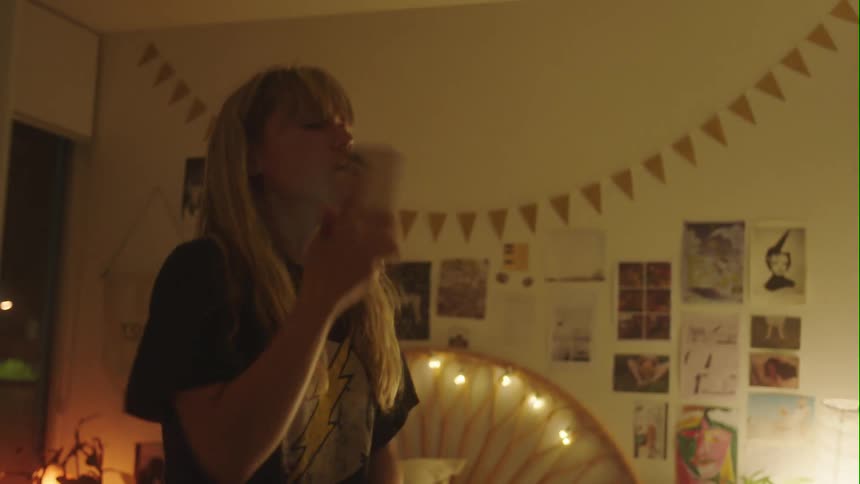 A girl scrolls through her phone while standing in her bedroom