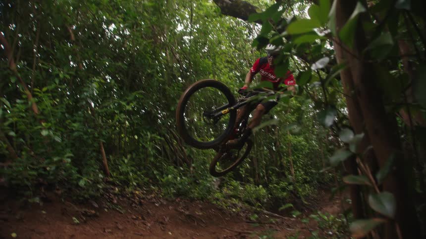 A young white man is riding there back down a dirt trail in the woods