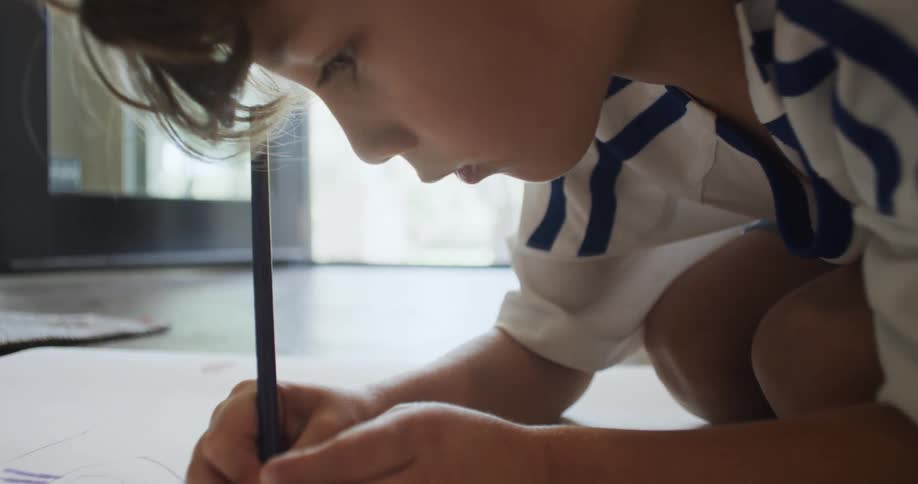 Boy drawing on paper on the floor suddenly stands and steps on paper while running off