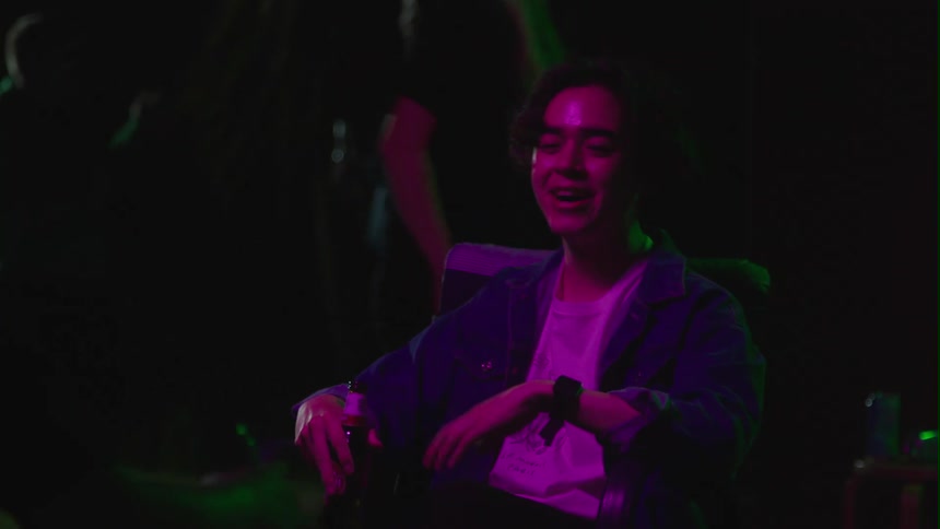 A young teenage boy is sitting down at a party and drinking some beer