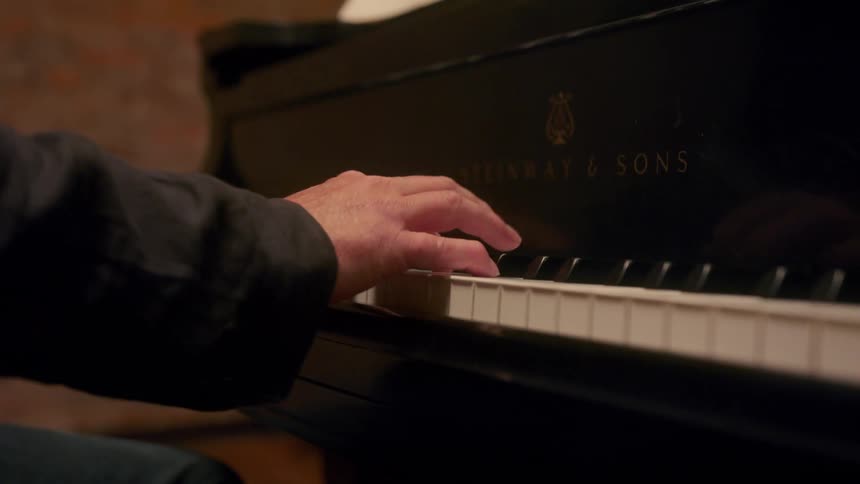 A person is playing the piano in there room in the day time