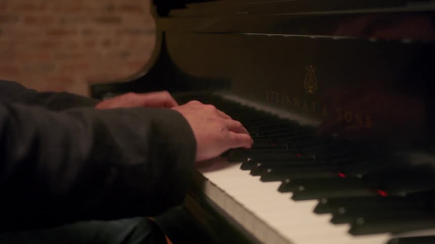 A young man is playing the piano in his home around the day time