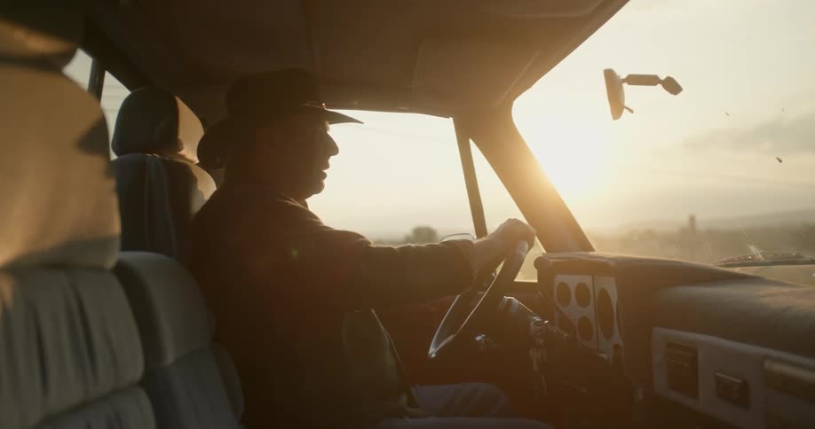 A man is sitting in his truck while the sun is setting