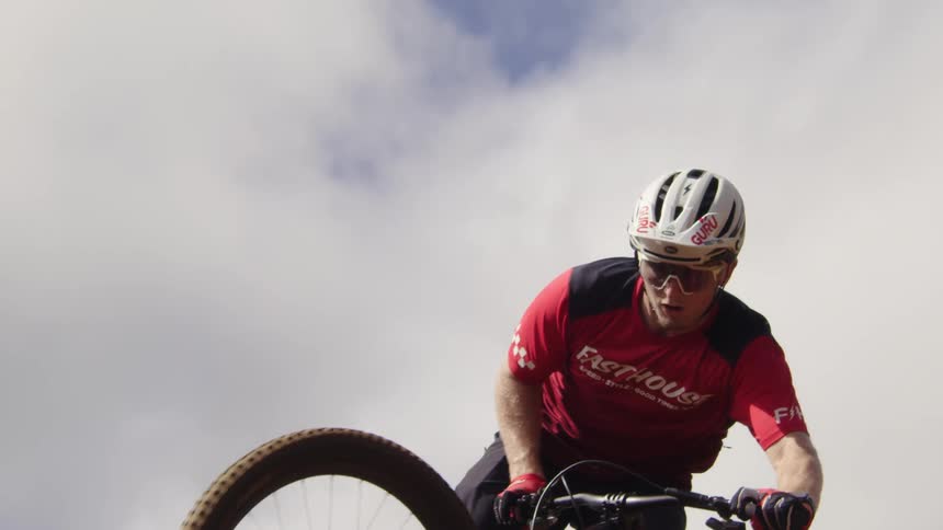 A teenage boy on a bicycle wearing a helmet is flying in the air and coming in for a landing as he holds the handlebars