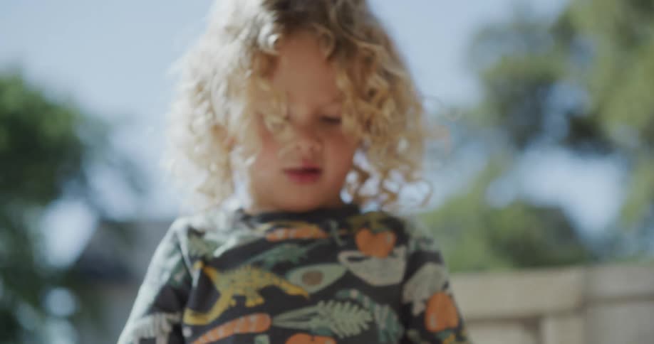 A little girl is standing outside leaning over a table coloring with crayons