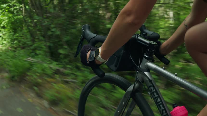 A woman is riding a bicycle on a path through the woods