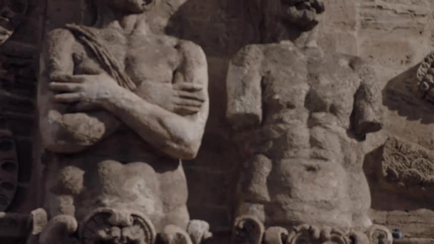Old statues of people on outer wall of building