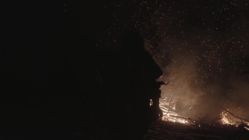 A fire rages as a person watches at night