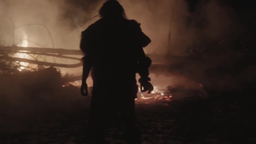 A man approaches fallen tree limbs that are on fire