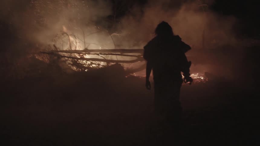 A man walks towards a fire