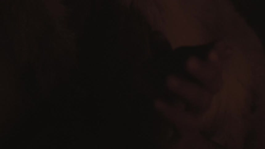 A man sits in the dark with hands clasped
