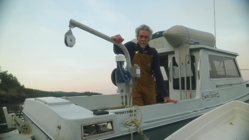 Fisherman stands in his fishing boat leaning against pot puller