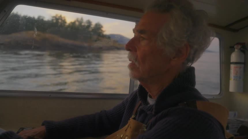 A man is sitting in a boat looking around as he steers it towards land
