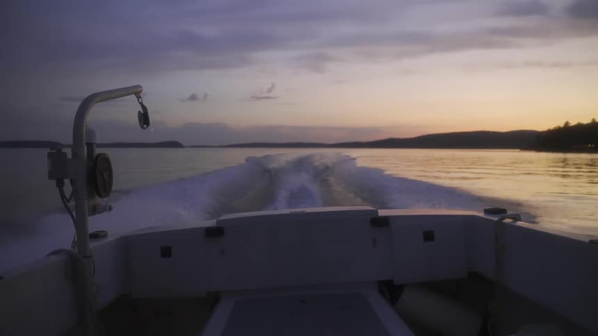 Moving out of the cabin of a motor boat watching the wake in the water at sunset