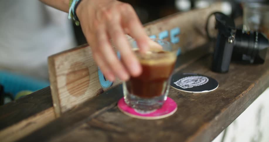 A man places a drink on the counter of an outdoor cafe