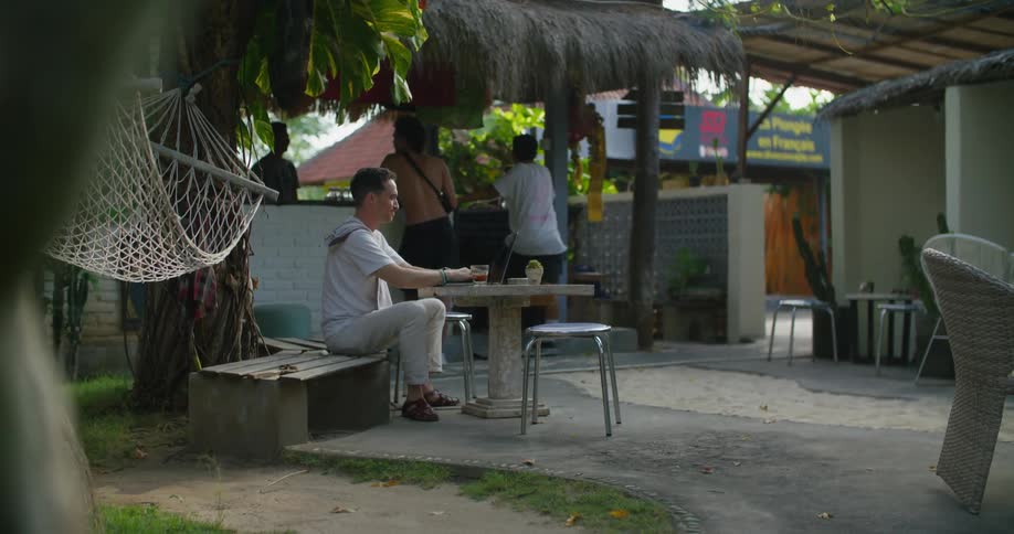 Tourist sitting on a small tropical town restaurant enjoying a drink while waiting