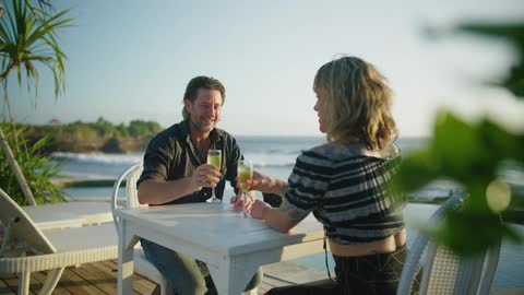 A couple have drinks on the beach