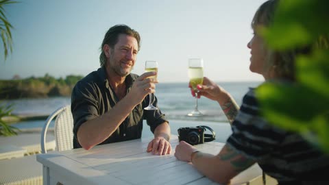 A man and woman have drinks on the beach