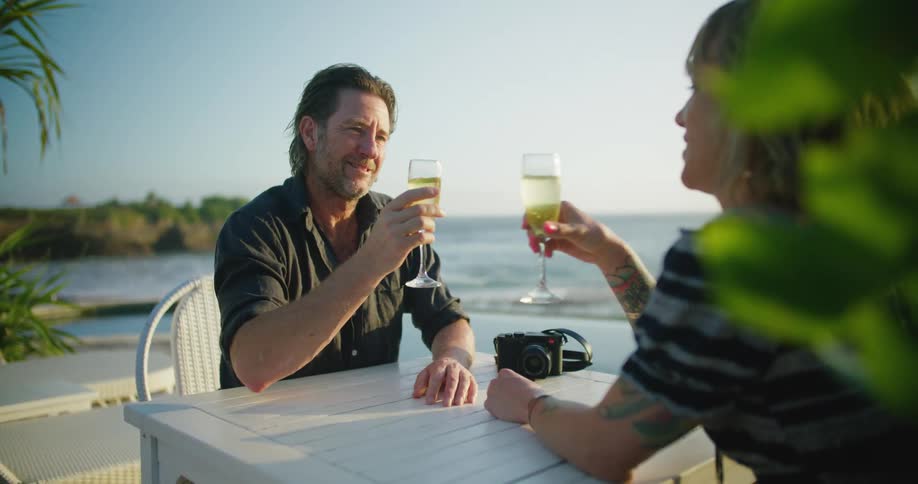 A man and woman have drinks on the beach